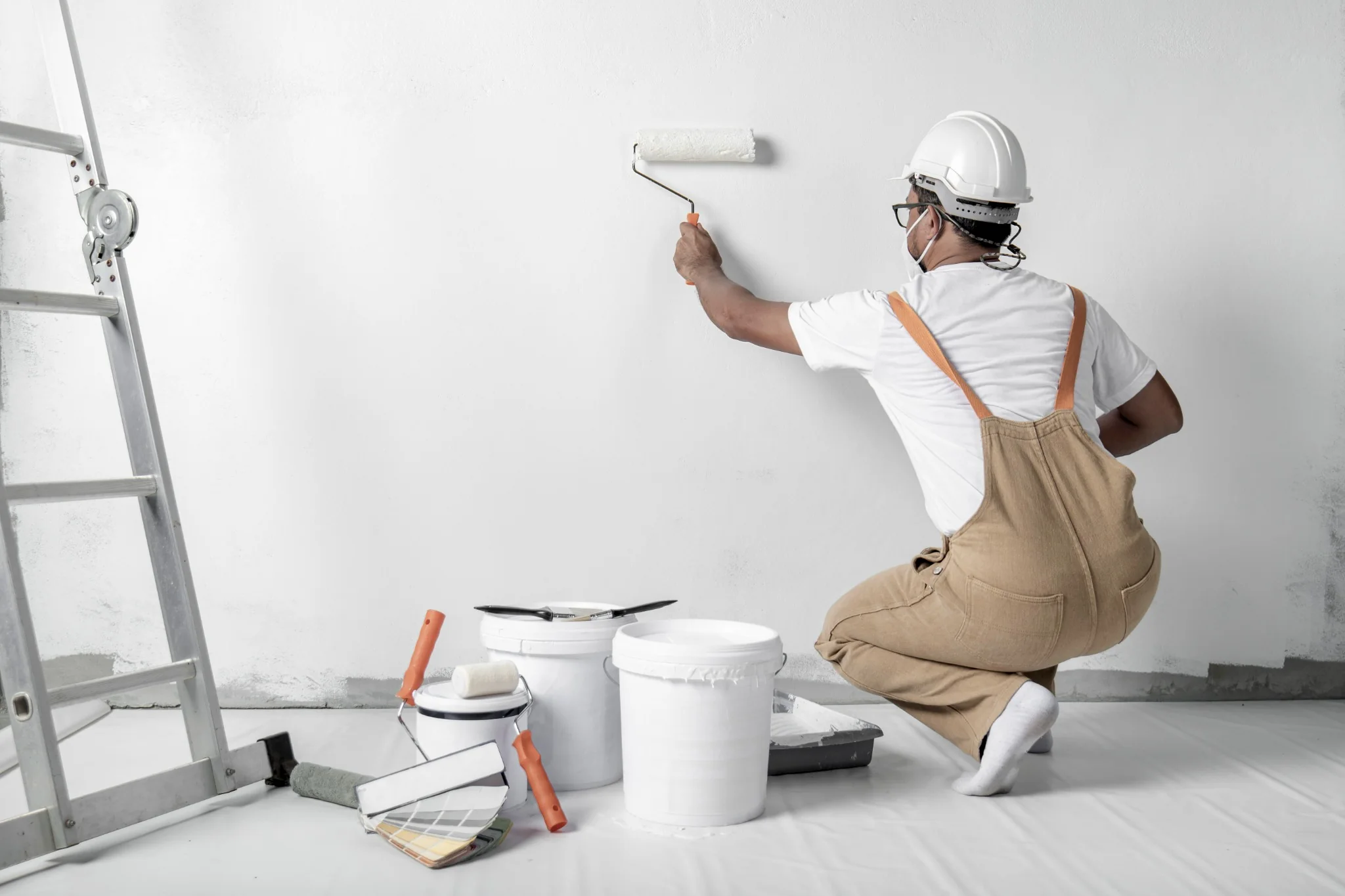 Professional interior painter using a roller on a white wall